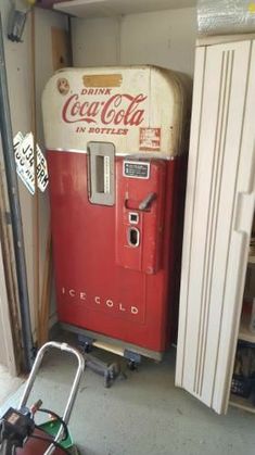 an old coca - cola machine sitting in a garage