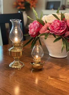 two vases with flowers in them sitting on a table next to a candle holder