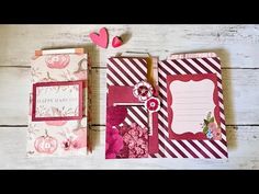 two small notebooks are sitting next to each other on a white wooden surface with pink flowers and hearts