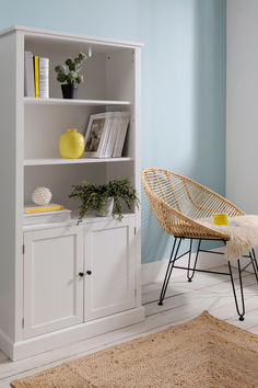 a wicker chair sits in front of a white bookcase