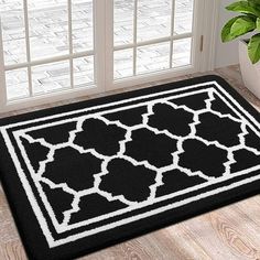 a black and white door mat in front of a potted plant on the floor