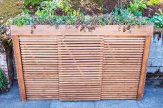 an outdoor wooden planter with plants growing on the top and bottom part of it