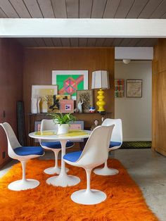 an orange rug in the middle of a room with white chairs and a round table