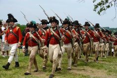 a group of men in red uniforms marching down a field with their backs turned to the camera