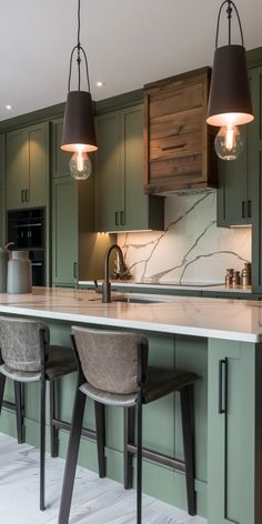 a kitchen with green cabinets and two pendant lights hanging over the bar area, along with stools