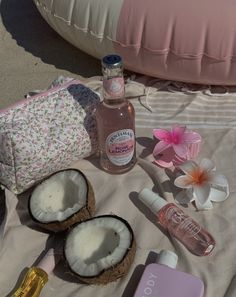 the contents of a bag are laid out on a beach towel next to coconuts