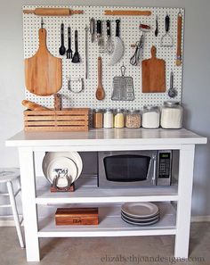 a white kitchen island with utensils hanging on the wall and various cooking tools