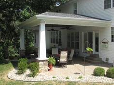 a white house with a covered patio in the front yard