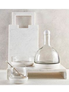 an assortment of glassware on a white shelf with a marble block in the background