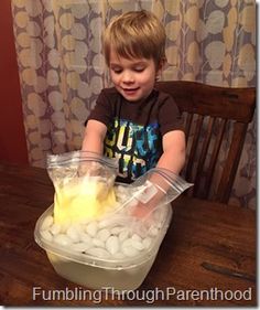 a young boy sitting at a wooden table with food in a container on top of it