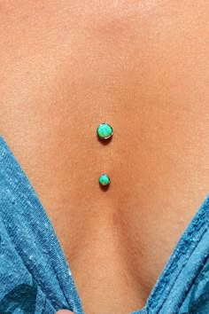 the back of a woman's stomach with two green stones on top of it