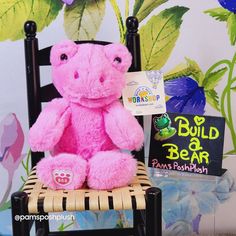 a pink teddy bear sitting on top of a wooden chair