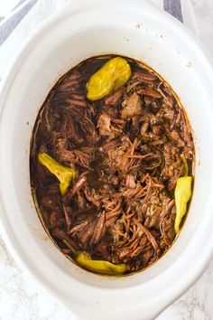 a white bowl filled with shredded beef and jalapenos on top of a table