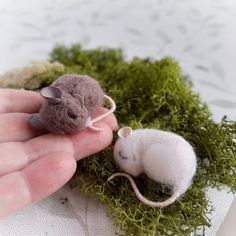 a hand holding a tiny toy mouse in it's palm next to another small one