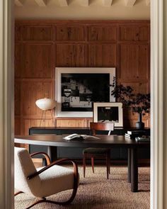 an office with wood paneling and chairs in the corner, along with pictures on the wall