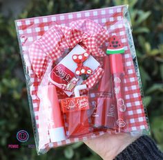 a person holding up a red and white box with lipstick, lip balm, watermelon