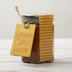 a jar filled with jam sitting on top of a wooden table next to a sign