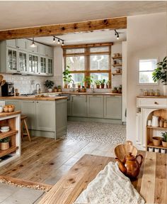 a large kitchen with wooden floors and green cabinets, white walls and wood flooring