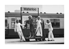 four women are standing in front of a train