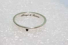 a wedding ring with the words always and forever engraved on it sitting on a white surface