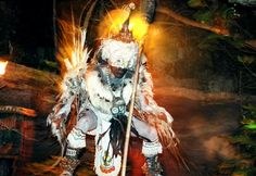 a man dressed in native american clothing holding a stick