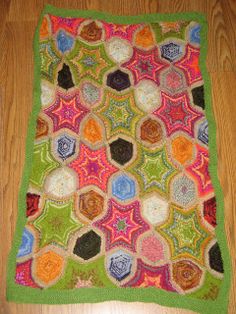 a multicolored crocheted blanket on the floor