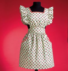 a mannequin wearing a dress with red and green flowers on it, in front of a pink background