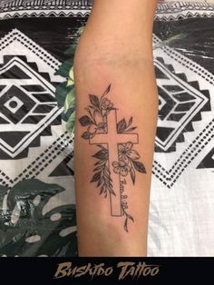 a cross with flowers and leaves on the side of his leg tattoo by busho tattoo