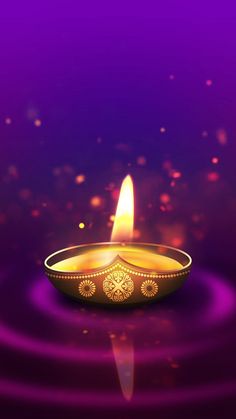 a lit diya on purple background with water and sparkles in the dark space