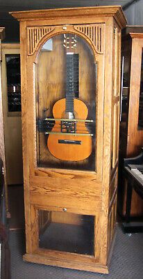 an old wooden clock with a guitar on it's display case in a store