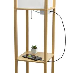 a small wooden shelf with a plant on top and an electronic device attached to it