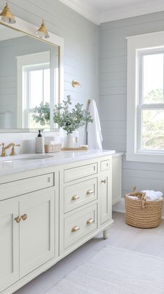 a bathroom with white cabinets and gold hardware on the handles, along with a large mirror