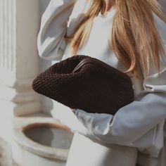 a woman in white shirt holding a brown purse