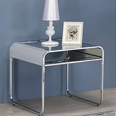 a white lamp sitting on top of a glass table next to a mirror and framed photograph