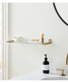 a bathroom sink with soap and toothbrushes on the shelf next to it, in front of a mirror