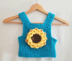 a blue crocheted top with a yellow flower on the front and brown center