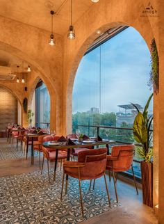 an empty restaurant with tables and chairs overlooking the city outside, along with large arched windows