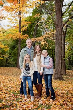 a family posing for a photo in the leaves