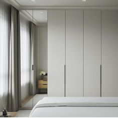 a white bed sitting in a bedroom next to a tall closet with sliding doors on both sides