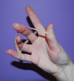 a person's hand holding a piece of tape in the air with their fingers