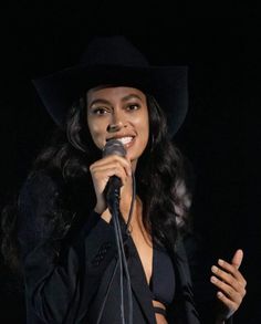 a woman wearing a black hat and holding a microphone