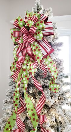 a christmas tree decorated with green and red ribbon, bows and polka dot bow on top