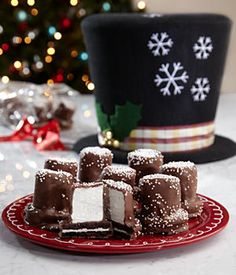 marshmallows on oreos dipped in chocolate sitting on a plate next to a christmas tree