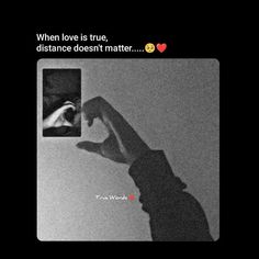 someone holding their hand up in front of a black and white photo with the words, when love is true, distance doesn't matter