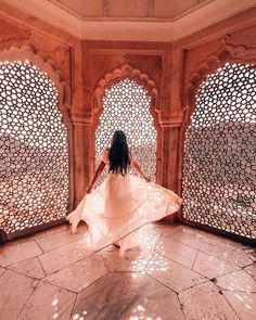 a woman in a white dress is walking through an archway