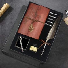 a pen, quill - pen, and notebook in a box on a table