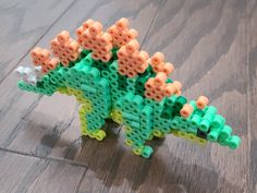 a toy dinosaur made out of legos on a wooden floor