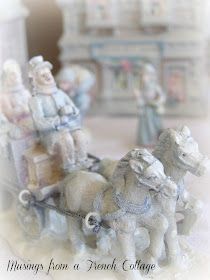 two figurines of people riding on a horse drawn carriage