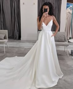 a woman in a white wedding dress taking a selfie with her cell phone while standing on the floor