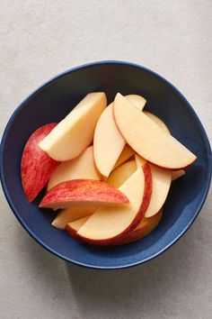 sliced apples in a blue bowl on a white counter top, ready to be eaten